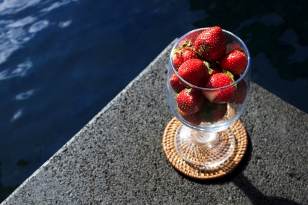 Strawberries in a glass beside a poolの写真素材