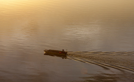 Silhouette of a moving boat at sunrise in Sabah, Malaysia, Borneoの写真素材