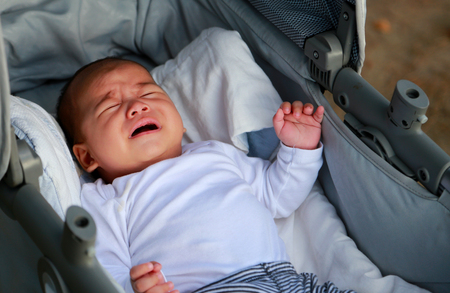 Cute newborn baby boy crying in a strollerの写真素材