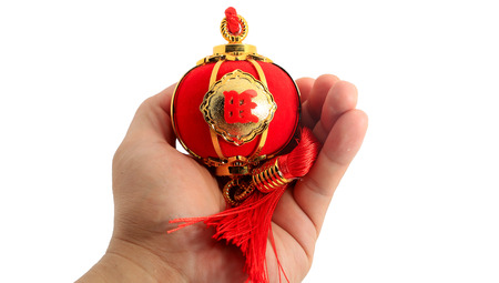 Hand holding a red spherical shape lantern for Chinese New year decoration isolated on whiteの写真素材