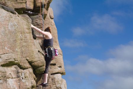 female rock climber climbing cliff faceの写真素材