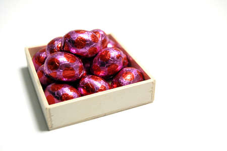 A small wooden crate filled with tasty red chocolate Easter eggsの写真素材