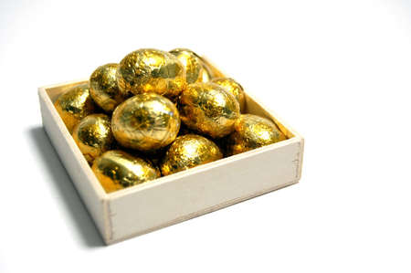 A small wooden crate filled with tasty golden chocolate Easter eggsの写真素材
