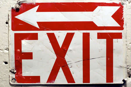 A weathered metal exit sign on a wall.の写真素材