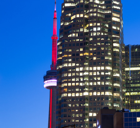 TORONTO, CANADA - 18 AUGUST 2014: The CN Tower appearing at the side of an office building in downtown Toronto at duskのeditorial素材