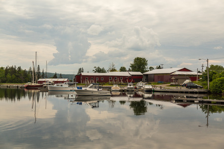 BADDECK, CANADA - 5TH JULY 2015: Boats and buildings at a harbour in Baddeck during an overcast day in the summer.のeditorial素材