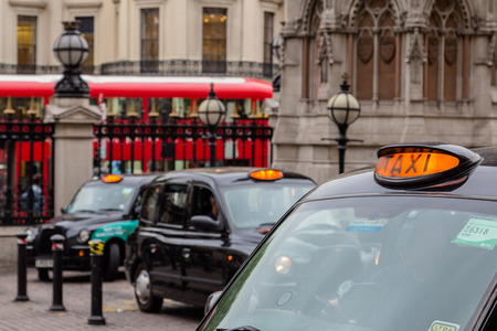 LONDON, UK - 20TH JULY 2015: Lots of parked Taxi's in London during the day. A red double decker bus can be seen in the background.のeditorial素材