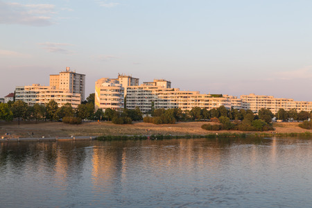 VIENNA, AUSTRIA - 3RD AUGUST 2015: A view of buildings along the Danube River in Vienna at sunset. People can be seen.のeditorial素材
