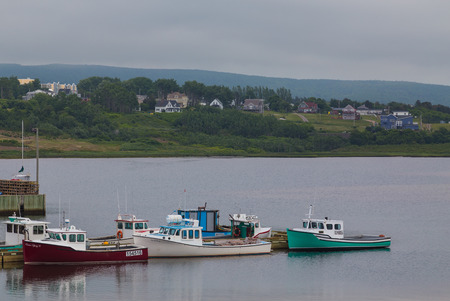 INVERNESS, CANADA - 6TH JULY 2015: Boats docked at a harbour in Inverness in Cape Breton Canada. Buildings can be seen in the distance.のeditorial素材