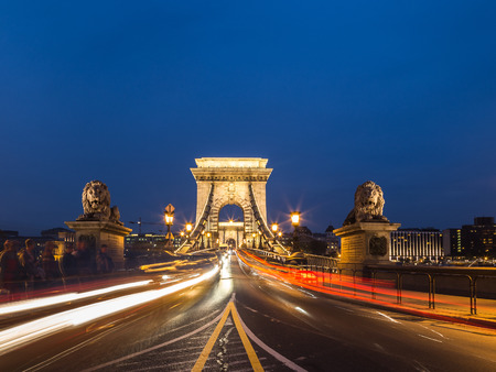The front of the Szechenyi Chain Bridge in Budapest Hungary. Trails from traffic can be seen. The people are blurred  out.の写真素材