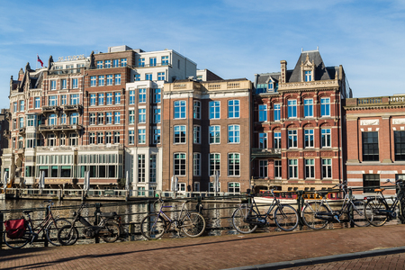 AMSTERDAM, NETHERLANDS - 16TH FEBRUARY 2016: Bicycles attached to railings along the canals in Amsterdam during the day. Buildings can be seen in the background.のeditorial素材