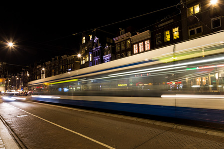 AMSTERDAM, NETHERLANDS - 16TH FEBRUARY 2016: A tram moving along a road in Amsterdam at night showing blurred motion.のeditorial素材