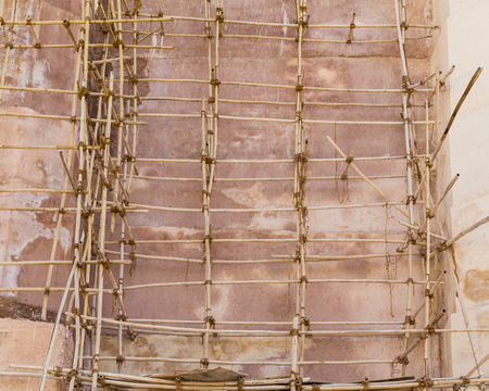 Scaffolding at the side of a wall in India made from Bamboo