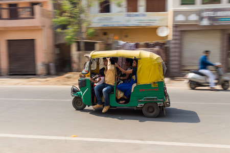 AGRA, INDIA - 26TH MARCH 2016: A Tuk Tuk Rickshaw movong along a road in Agra during the day. Lots...