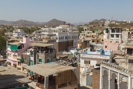 UDAIPUR, INDIA - 20TH MARCH 2016: A high view over rooftops in Udaipur during the day. The outside of buildings and hills can be seen.のeditorial素材