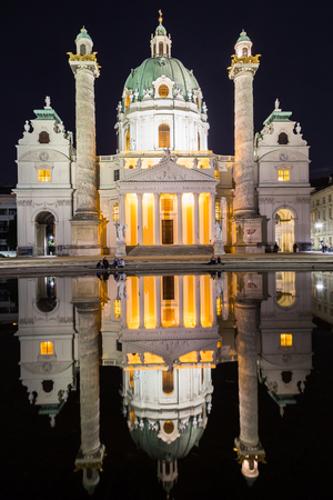 VIENNA, AUSTRIA - 17TH APRIL 2016: The outside of Karlskirche in Vienna at night. Reflections and people can be seen.のeditorial素材
