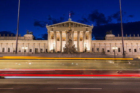 The outside of the Austrian Parliament building in Viennat at night. The blur of a tram can be seen going past in the foreground.の写真素材