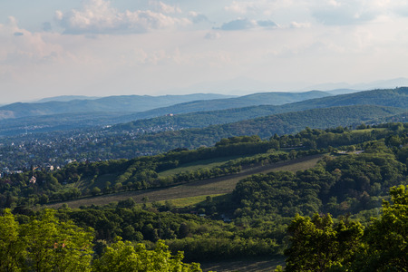 A view over the Vienna woods in the Spring showing hills, trees and some buildingsの写真素材