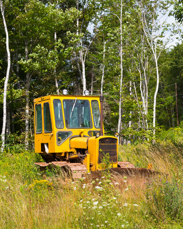 NOVA SCOTIA, CANADA - 27TH AUGUST 2014: A small bright yellow tractor parked in a field.
