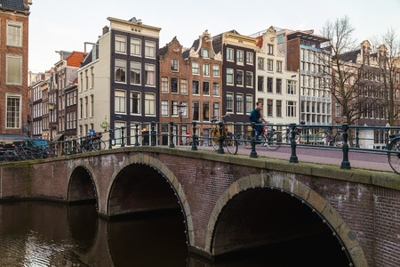 AMSTERDAM, NETHERLANDS - 17TH FEBRUARY 2016: Bridges and buildings in the Centrum district of Amsterdam during the morning. A cyclist can be seen.のeditorial素材