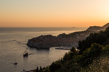 A ?high view of Dubrovnik Old Town at sunset showing the outside of buildings, boats and the sea.の写真素材