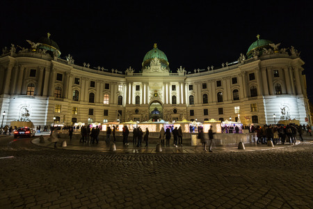 VIENNA, AUSTRIA - 2ND DECEMBER 2016: The outside of the Hofburg Palace from Michaelerplatz in Vienna at night. Christmas Market Stalls and large amounts of people can be seen outsideのeditorial素材