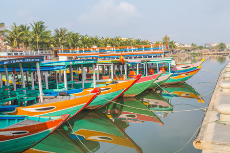 HOI AN, VIETNAM - 25TH MARCH 2017: Colourful tour boats along the waterfront and Thu Bon River in Ancient Town Hoi An during the morning. Reflections can be seen in the water.のeditorial素材
