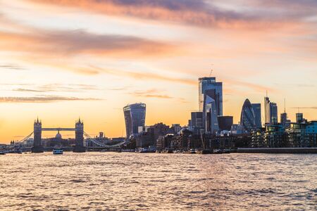 Tower Bridge and buildings in the City of London at sunset. Skyscrapers and office buildings can ber...
