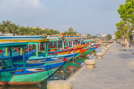 HOI AN, VIETNAM - 25TH MARCH 2017: Colourful tour boats along the waterfront and Thu Bon River in Ancient Town Hoi An during the morning. Reflections can be seen in the water.のeditorial素材