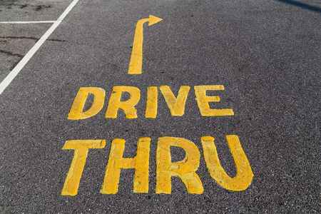 A sign for a drive through (drive thru) on a road. Written in yellow paint.の写真素材