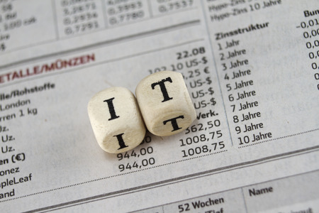 IT Word Built with letter cubes on newspaper background