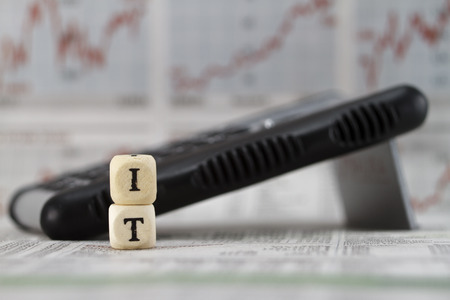 IT Word Built with letter cubes on newspaper background