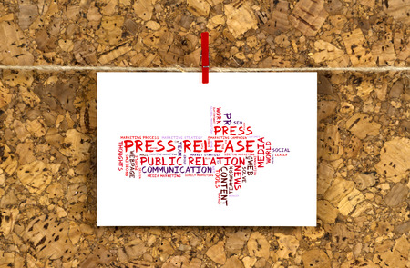 Business card with Press Release word cloud shaped as a arrow to the right on a cork pinboard