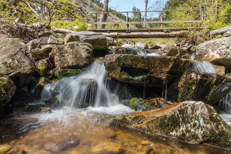 Cascade creek and wooden footbridge - detail from spring countryside in Czech Republic
