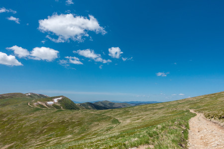 Road through the amazing mountain spring under blue sky with white clouds Svydovets Range Carpathians West Ukraineの写真素材