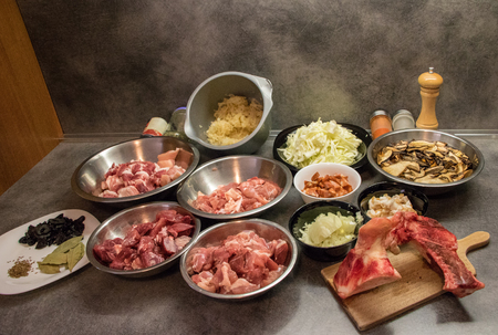 Cooking ingredients on kitchen table - dishes with meat, mushrooms, onion, sausage, cabbage, condiment etc.の写真素材