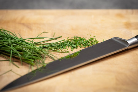 Knife and sliced chives on wooden kitchen board - detail from kitchen