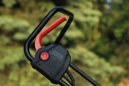 Safety switch on the mower mowing the grass in the garden
