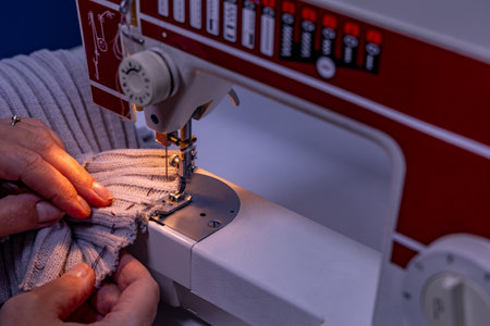 Sewing on a machine at home in a tailor's shop, repairing old clothes