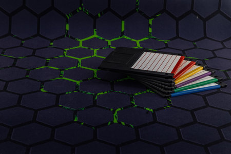Colorful old floppy disks for old 16-bit and 8-bit 3.5-inch computers arranged on a black keyboard and mouse padの写真素材