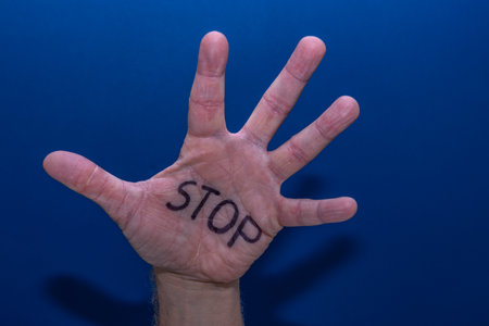 A hand on a blue background of a man calling for help, a symbol, a cry for help, an attempt to stop violence, stop hate on the Internet, at schoolの写真素材