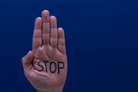 A hand on a blue background of a man calling for help, a symbol, a cry for help, an attempt to stop violenceの写真素材