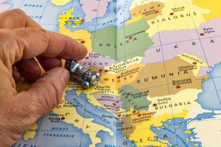 A colorful map of Europe, a small metal car in a man's hand shows the route to Croatiaの写真素材
