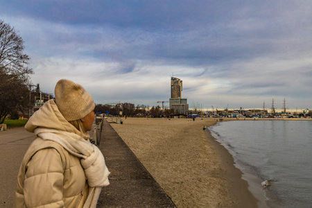 Walking along the Baltic coast towards Gdynia, woman in winter jacket, panorama of Gdyniaの写真素材