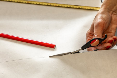 Cutting wallpaper before sticking it to the wall, scissors, measuring tape and pencil on the table,...