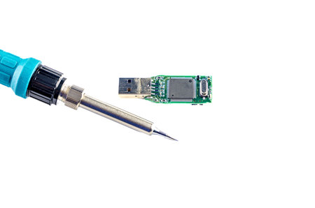 Soldering iron in the hands of a man who repairs a damaged flash drive, on a white background