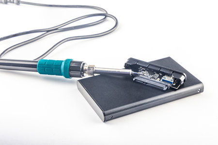 Damaged external drive, transformer soldering iron on white background, electronic equipment repair...