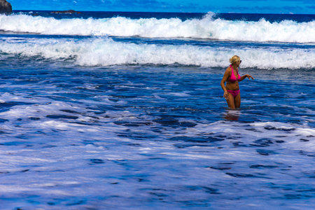 A woman in a pink swimsuit bathes in the Atlantic Ocean during high wavesの写真素材