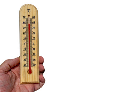 Wooden thermometer indicating high temperature, held in hand, measuring air temperatureの写真素材