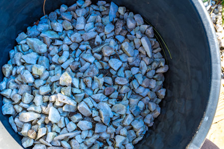 Pouring out small white decorative stones on the veranda in the garden, a bucket with stones for decorationの写真素材